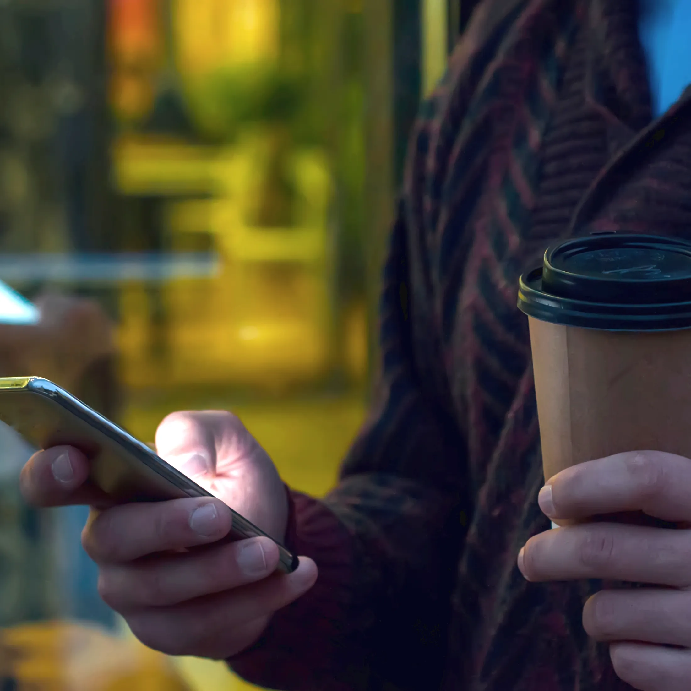 Personne consultant son smartphone en buvant un café